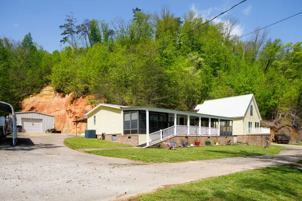 a view of a white house with a big yard and large trees