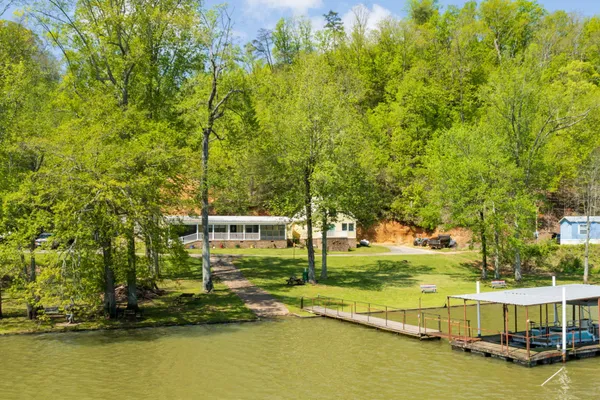 a view of a swimming pool with lawn chairs and large trees