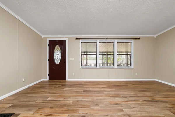 a view of an empty room with wooden floor and window