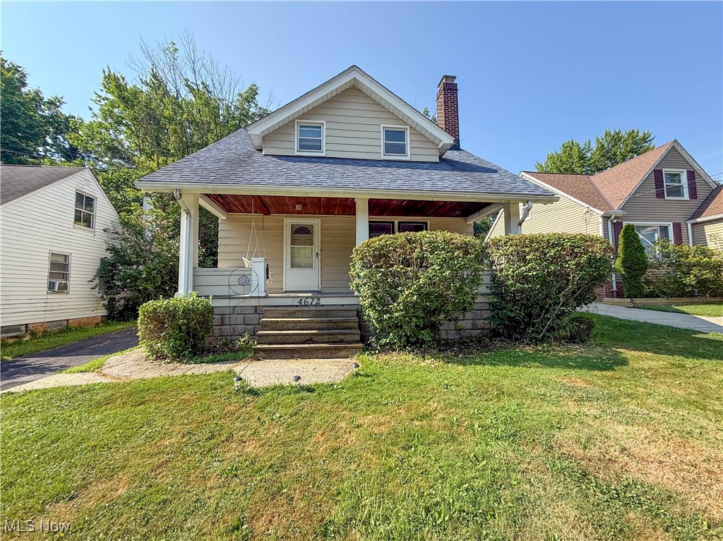 Bungalow with a porch, a chimney, a front yard, and a shingled roof