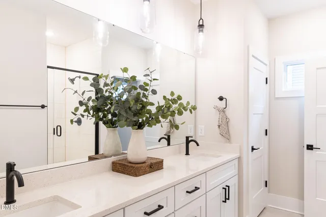 a bathroom with a double vanity sink a mirror a glass door a shower and vanity