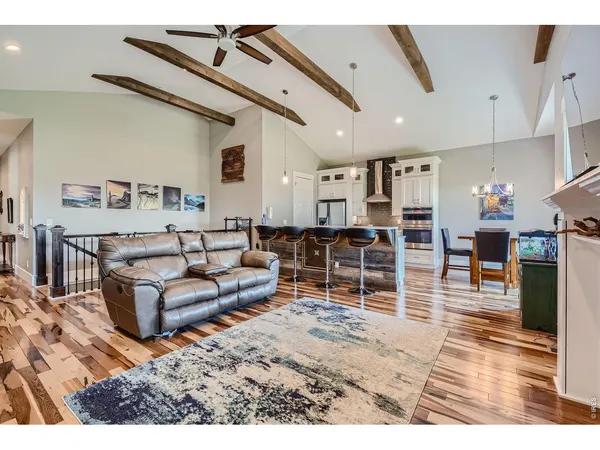 a living room with furniture a wooden floor and kitchen view