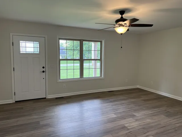 a view of an empty room with wooden floor and a window