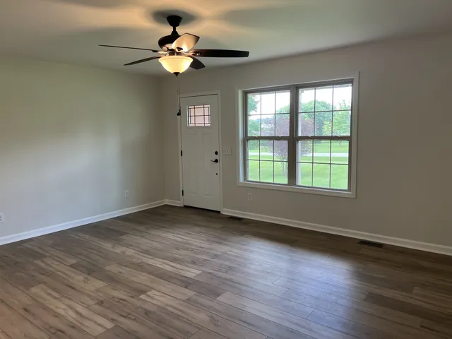 a view of an empty room with wooden floor and a window