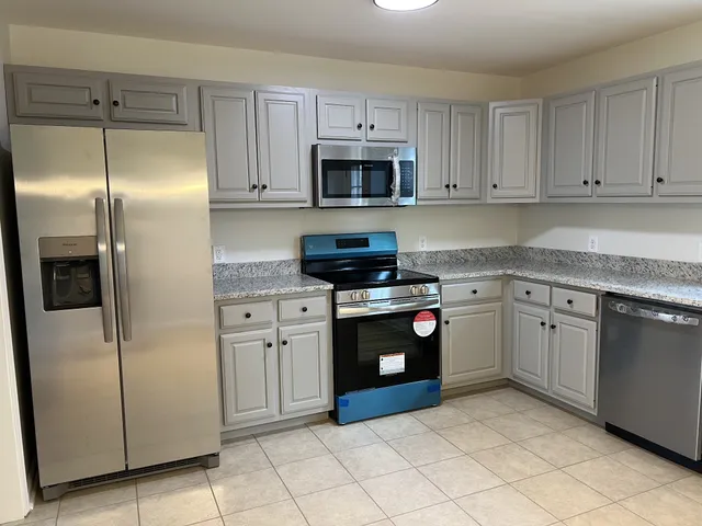 a kitchen with stainless steel appliances granite countertop a refrigerator and a stove top oven