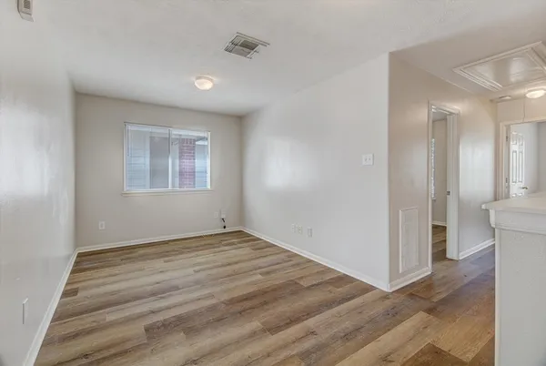 a view of an empty room with wooden floor and a window