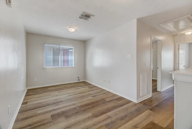 a view of an empty room with wooden floor and a window