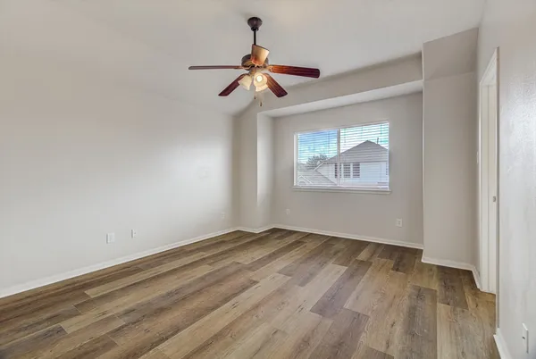 a view of empty room with wooden floor and fan