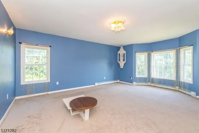 a view of an empty room with a window and kitchen