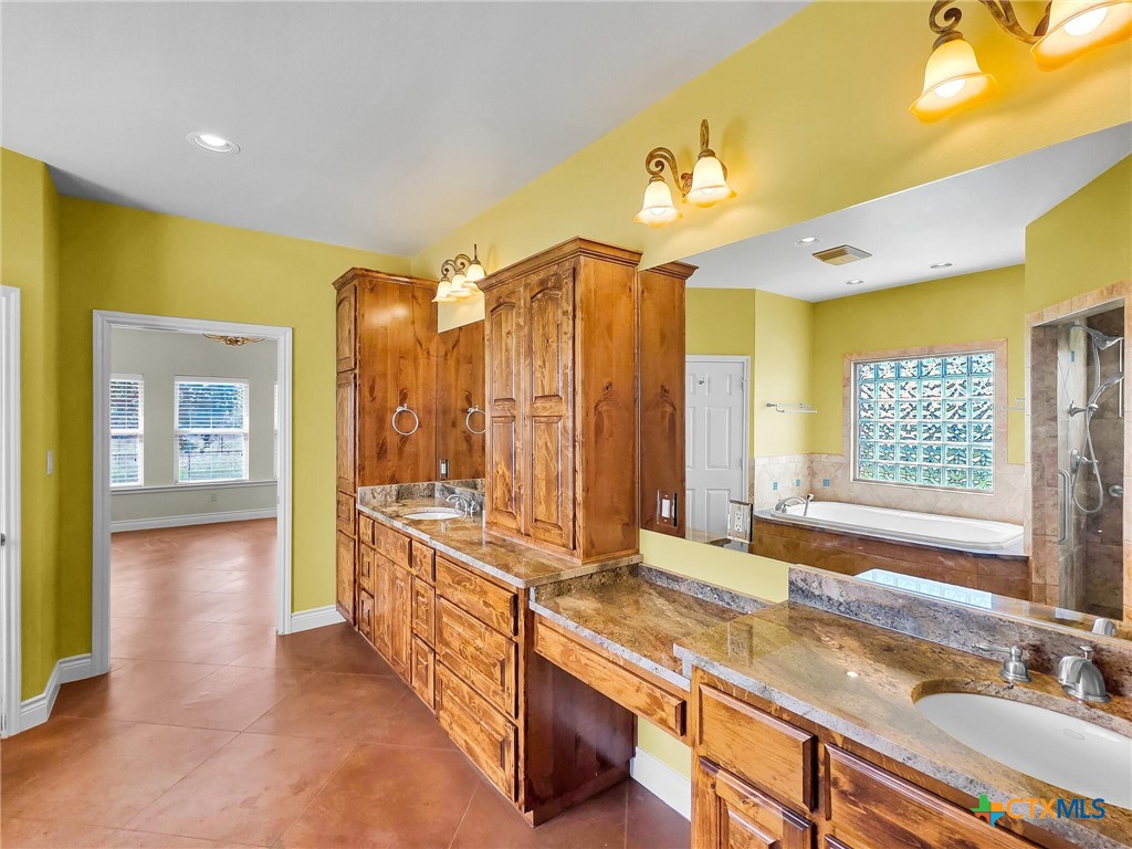 301 County Road 253 Bertram, TX 78605 - Photo 12 of 28 a spacious bathroom with a double vanity sink a large mirror and a bathtub