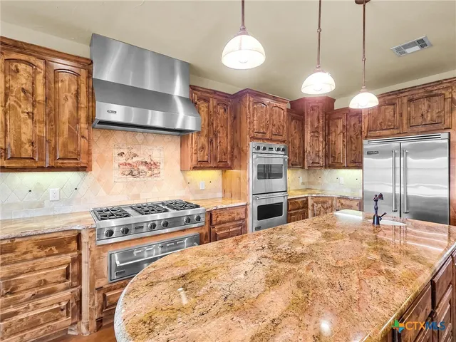 a kitchen with stainless steel appliances granite countertop a stove a sink and a refrigerator