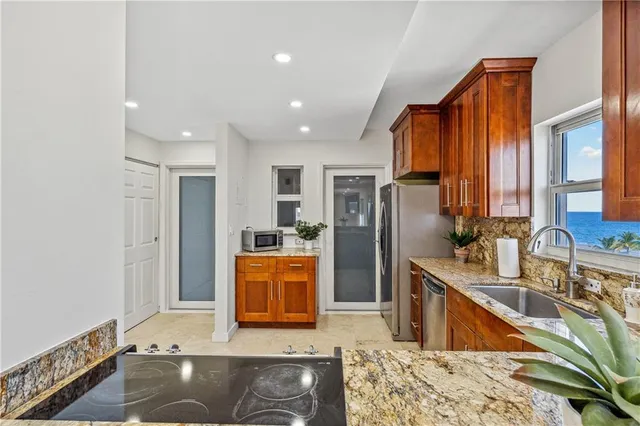 a kitchen with stainless steel appliances granite countertop a refrigerator a stove and a sink with wooden floor