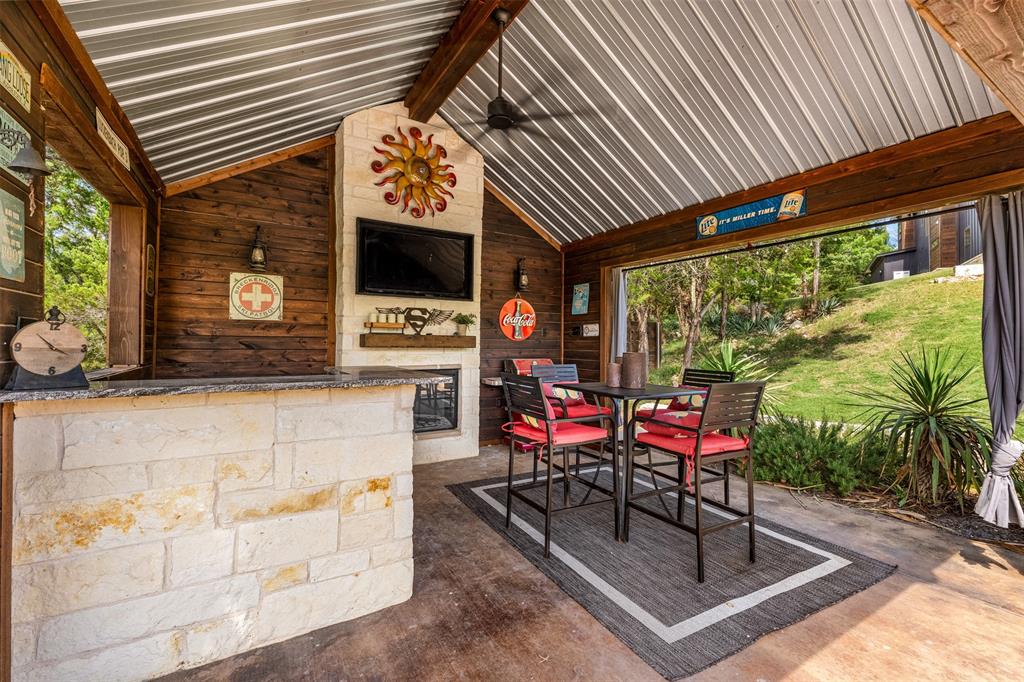 124 Bluffview Circle China Spring, TX 76633 - Photo 33 of 40 Covered outdoor entertainment area featuring a stone-clad bar with a countertop, a stone fireplace, and a wood-paneled accent wall