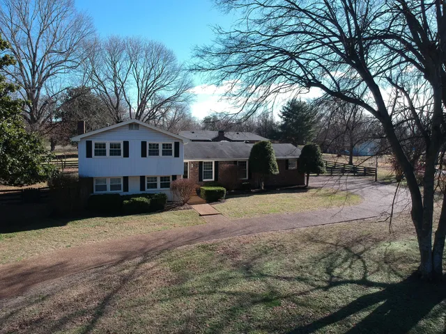 a front view of a house with a yard covered with snow and trees