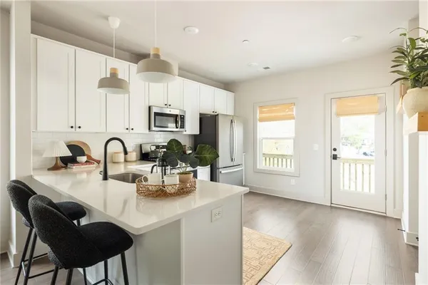 a kitchen with stainless steel appliances granite countertop a stove a sink dishwasher and a microwave with wooden floor