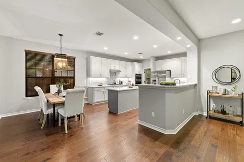 a living room with stainless steel appliances kitchen island granite countertop furniture wooden floor and a kitchen view