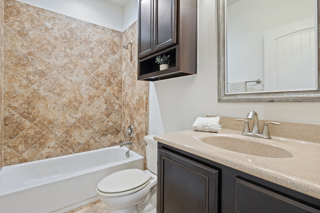 11217 Bastogne Loop Austin, TX 78739 - Photo 25 of 40 a bathroom with a granite countertop sink toilet a mirror and bathtub