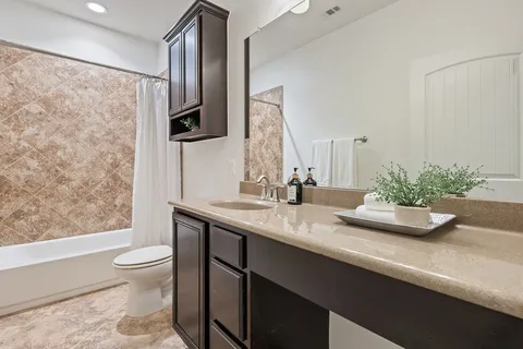 a bathroom with a granite countertop sink a toilet a mirror and shower