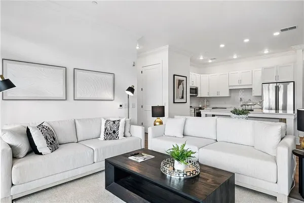 a living room with furniture kitchen and a potted plant