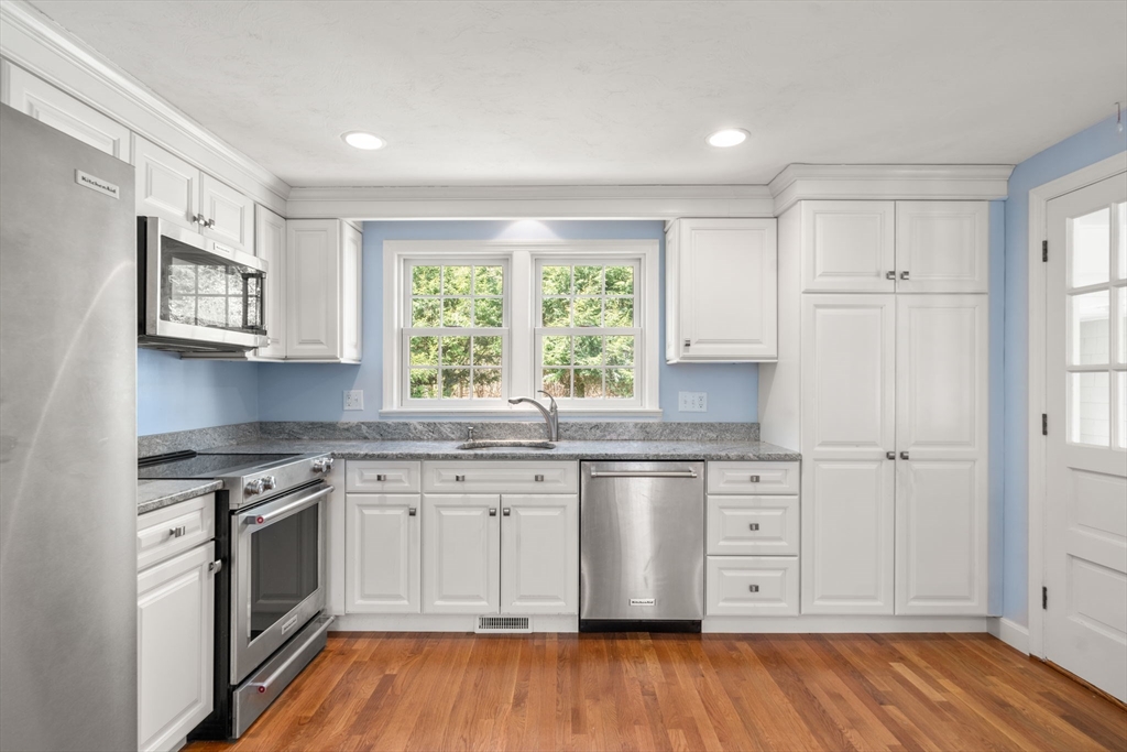 40 Amble Road Chelmsford, MA 01824 - Photo 8 of 26 a kitchen with stainless steel appliances granite countertop a stove a sink and white cabinets with wooden floor next to windows