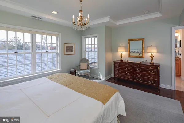 a spacious bedroom with a bed a dresser and chair