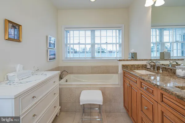 a bathroom with a granite countertop sink a bathtub window and mirror