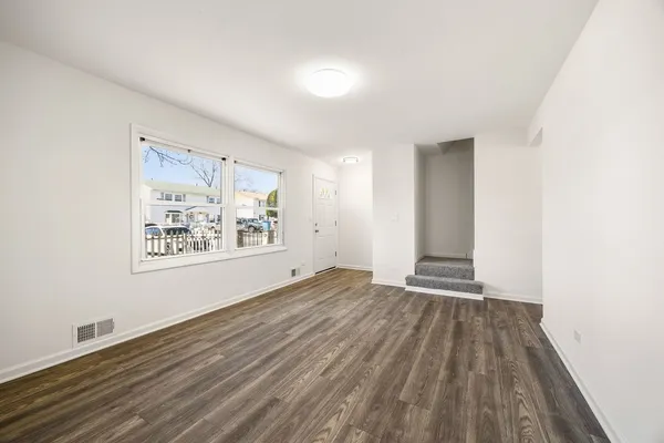 an empty room with wooden floor and window