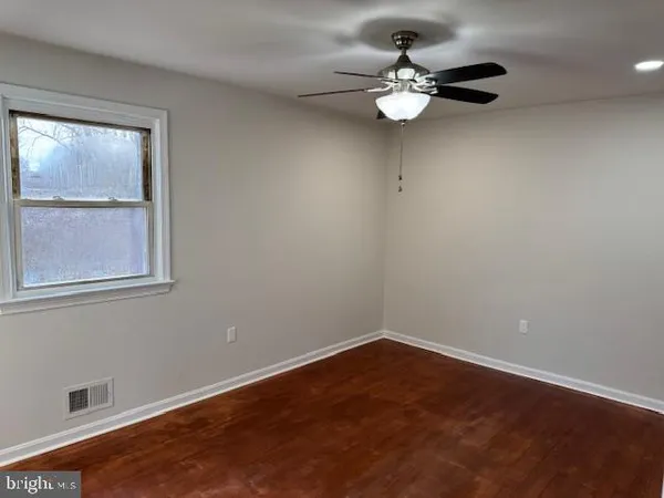 an empty room with wooden floor closet and windows