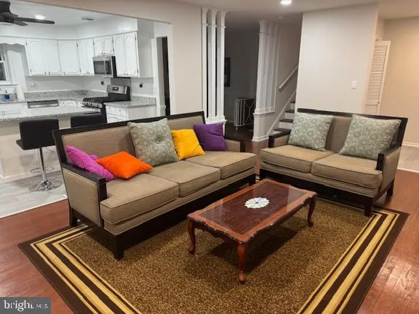 a living room with furniture a rug and kitchen view