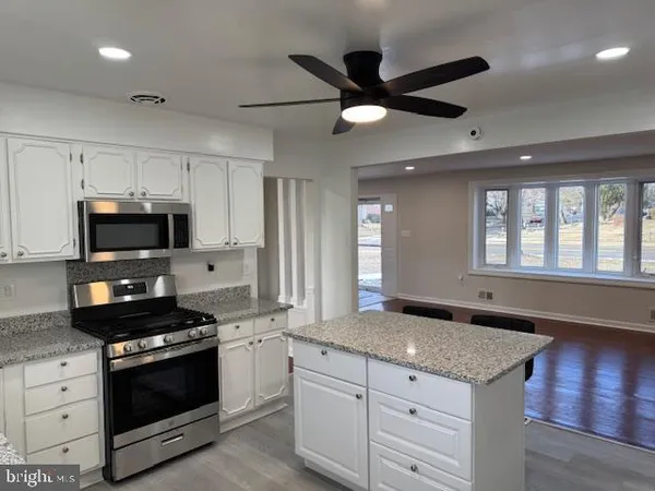 a kitchen with granite countertop stainless steel appliances a stove sink and microwave