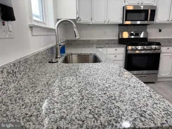 a kitchen with granite countertop a sink and a stove top oven
