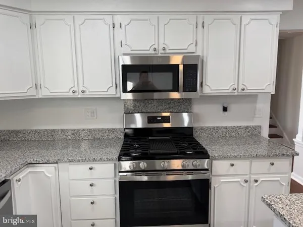 a kitchen with kitchen island granite countertop a sink cabinets and stainless steel appliances