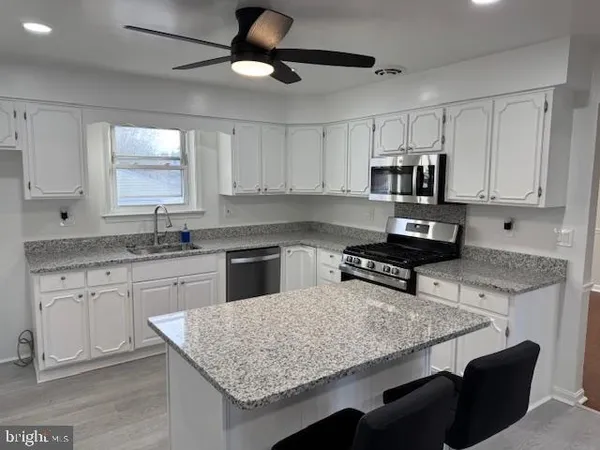 a kitchen with granite countertop white cabinets and stainless steel appliances