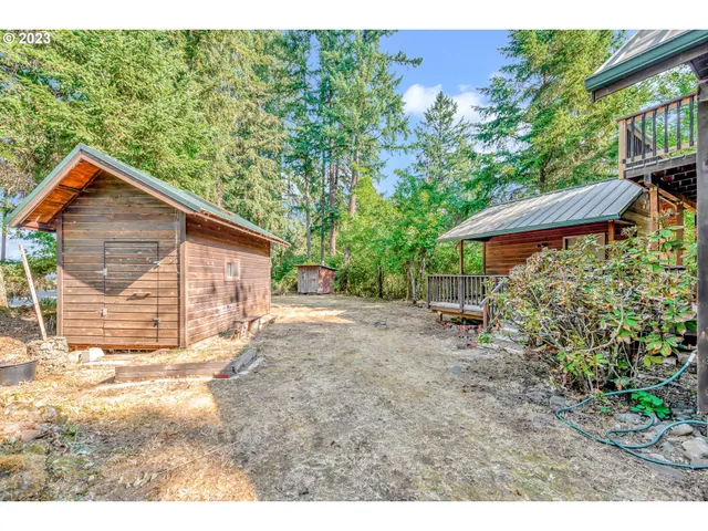 a backyard of a house with large trees and wooden fence