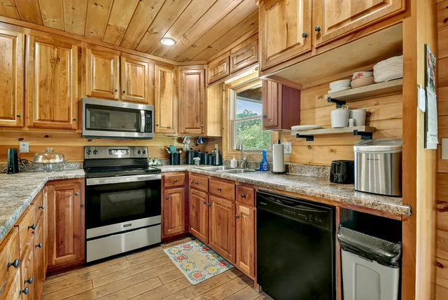 a kitchen with stainless steel appliances granite countertop a sink a stove and cabinets