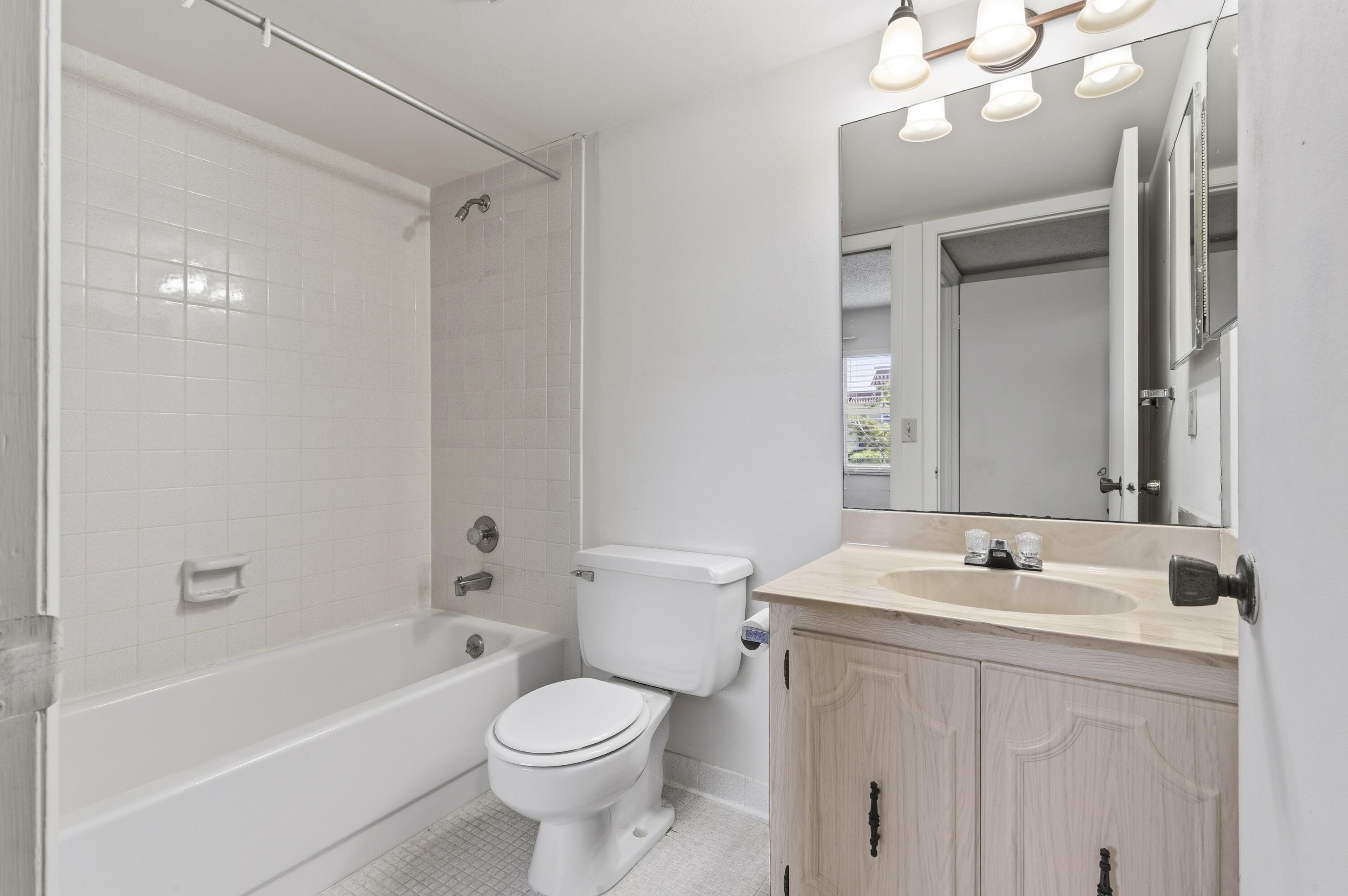 717 Highway 1, Unit 201 Jupiter, FL 33477 - Photo 13 of 31 a bathroom with a sink a toilet a mirror a vanity and bathtub