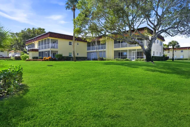 a front view of a house with a garden and trees
