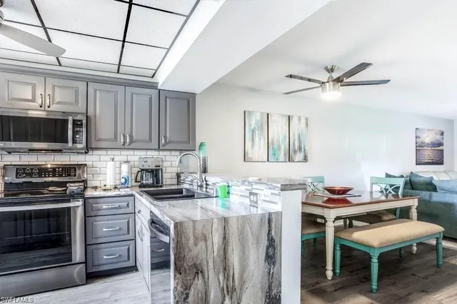 a kitchen with stainless steel appliances granite countertop a stove top oven a sink dishwasher and white cabinets with wooden floor