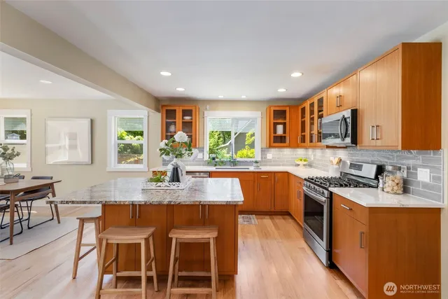 a kitchen with stainless steel appliances granite countertop a kitchen island hardwood floor sink stove dining table and chairs