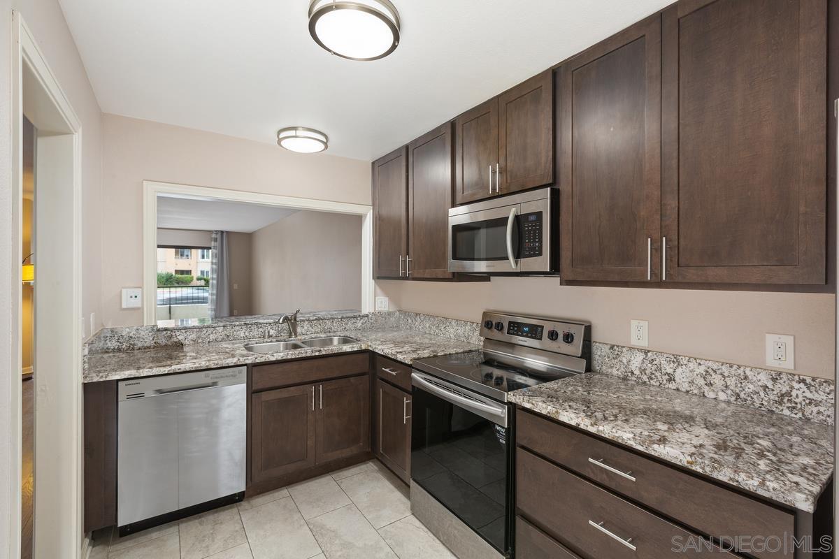 a kitchen with granite countertop stainless steel appliances a sink stove top oven and cabinets