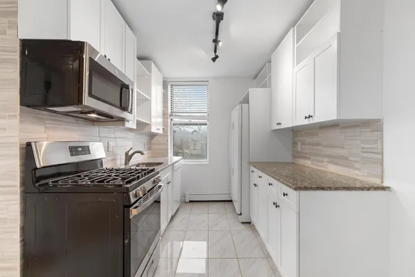 a kitchen with stainless steel appliances granite countertop a stove a sink and a microwave