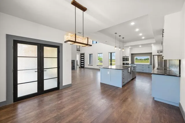 a living room with stainless steel appliances kitchen island granite countertop wooden floors and a large window