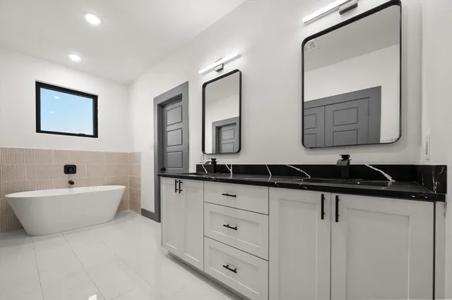 a bathroom with a granite countertop sink mirror and bathtub