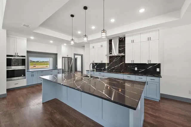 a kitchen with stainless steel appliances granite countertop a sink a stove and a wooden floors