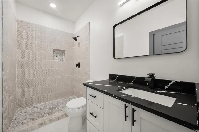 a bathroom with a granite countertop sink a toilet a mirror and shower