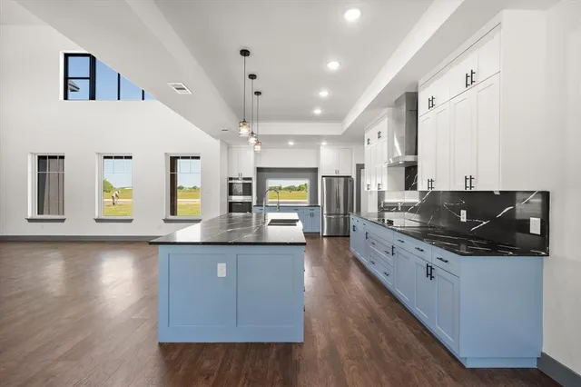 a large kitchen with stainless steel appliances kitchen island a large counter top and a stove top oven