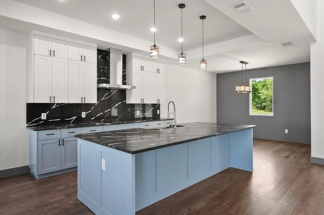 a kitchen with stainless steel appliances granite countertop a sink a stove and a wooden floors