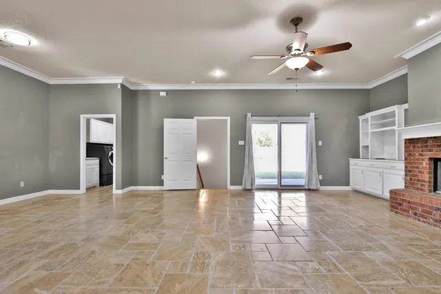 a view of an empty room with a chandelier fan and windows