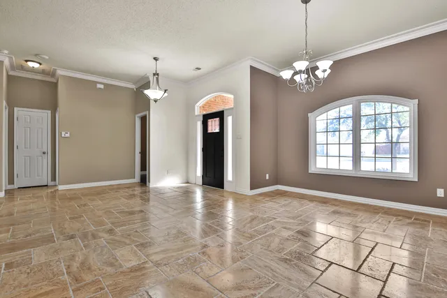 an empty room with chandelier and windows