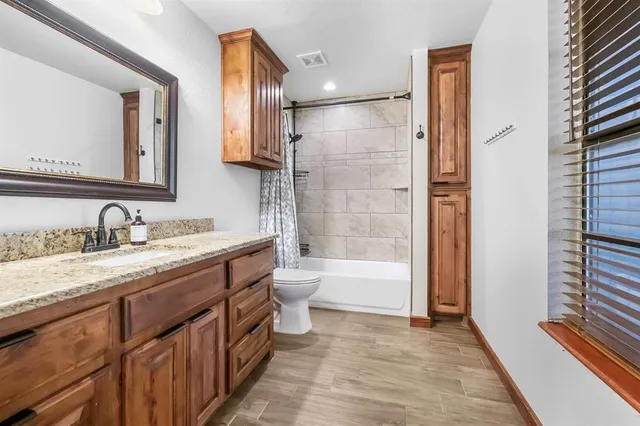 a bathroom with a granite countertop sink toilet and shower